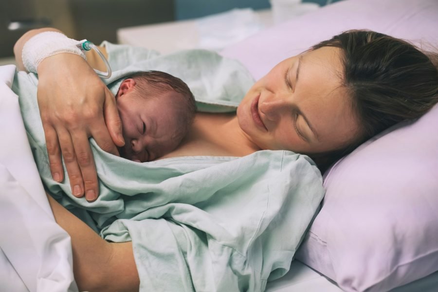 Mother and newborn. Child birth in maternity hospital. Woman giving birth.